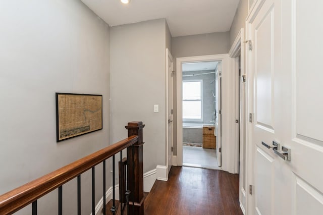 hall with baseboards, dark wood finished floors, and an upstairs landing