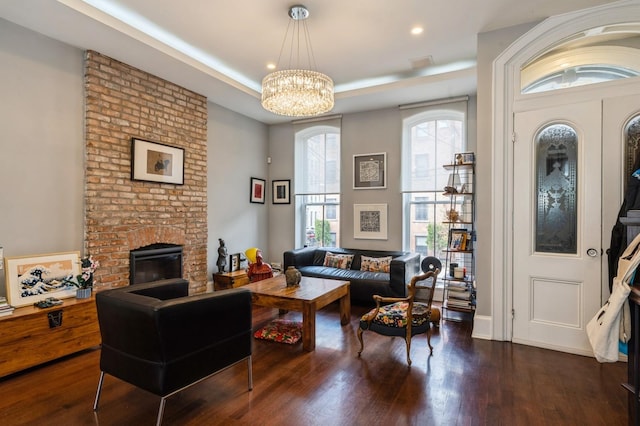 living room with a raised ceiling, a fireplace, a chandelier, recessed lighting, and wood finished floors