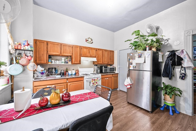 213 45th St, Union City, NJ 07087 - kitchen with appliances with stainless steel finishes, under cabinet range hood, light wood-style floors, light countertops, and brown cabinets