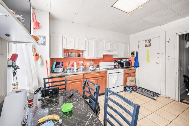213 45th St, Union City, NJ 07087 - kitchen with gas range gas stove, under cabinet range hood, a paneled ceiling, light tile patterned flooring, and open shelves