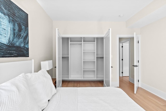 bedroom with wood finished floors, baseboards, and a closet