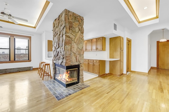 301 79th St Unit E4, North Bergen, NJ 07047 - unfurnished living room with a raised ceiling, light wood-style floors, ceiling fan, crown molding, and a stone fireplace