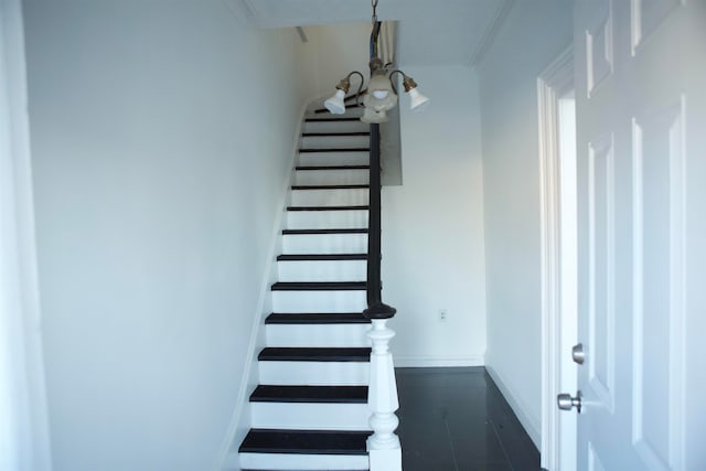 stairway with a notable chandelier and crown molding