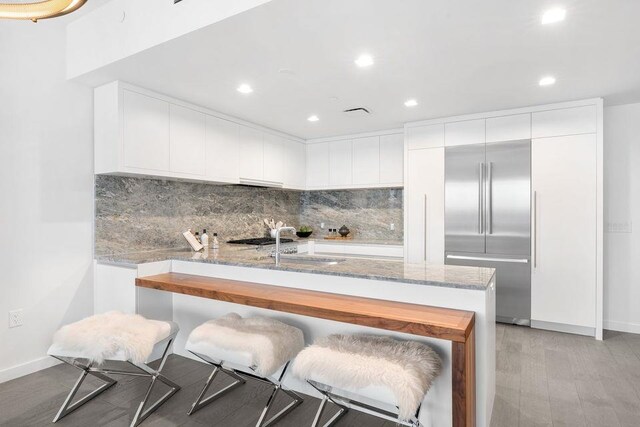 320 Adolphus Ave Unit 909, Cliffside Park, NJ 07010 - kitchen featuring recessed lighting, decorative backsplash, built in refrigerator, light stone counters, and white cabinetry