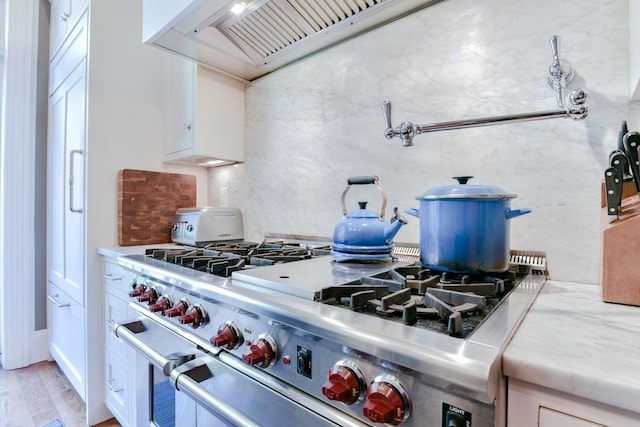 kitchen featuring light countertops, light wood-style flooring, high end range, and white cabinetry