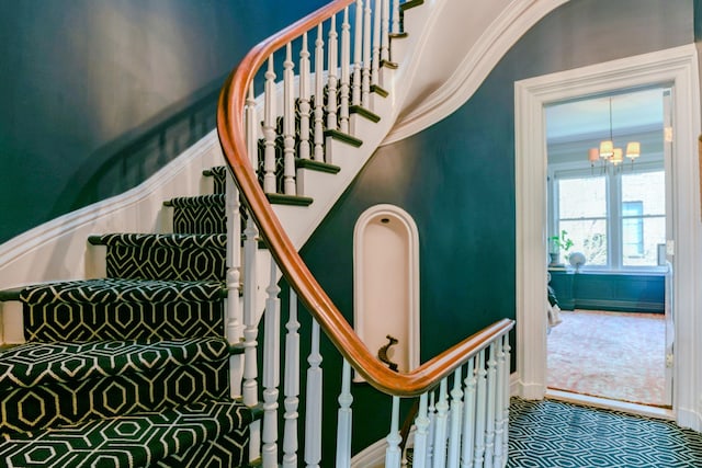 staircase with crown molding and a notable chandelier