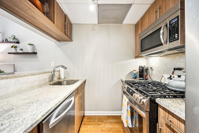 227 Christopher Columbus Dr Unit B-234, Jersey City, NJ 07302 - kitchen featuring appliances with stainless steel finishes, brown cabinets, light wood-style flooring, backsplash, and light stone countertops