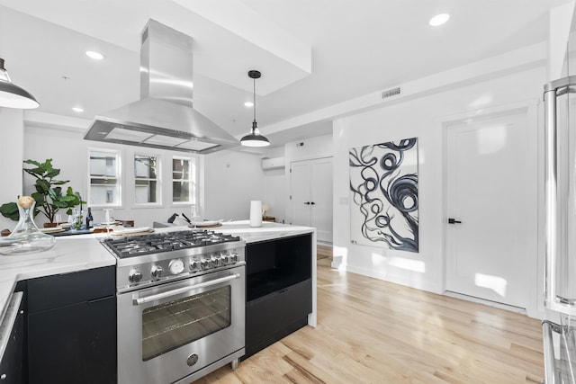 kitchen featuring visible vents, light wood finished floors, island exhaust hood, high end stainless steel range oven, and dark cabinets