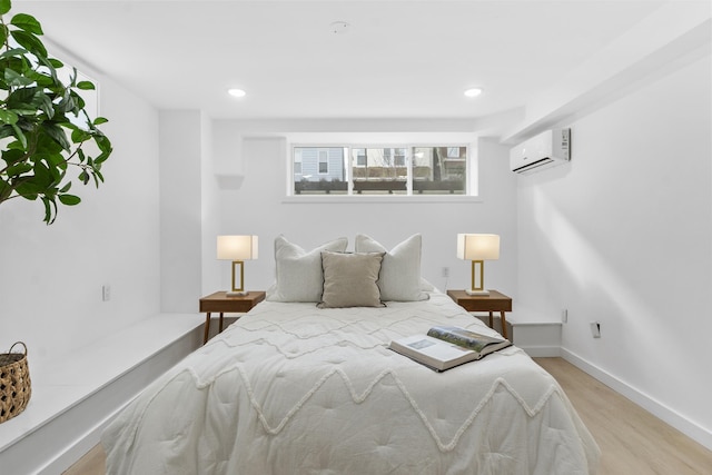 bedroom with a wall mounted air conditioner, baseboards, light wood-style flooring, and recessed lighting