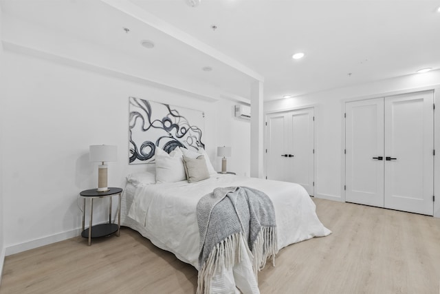 bedroom with recessed lighting, light wood-style floors, baseboards, and two closets