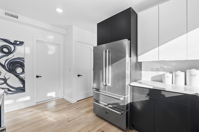 kitchen featuring dark cabinetry, light countertops, light wood-style floors, high end refrigerator, and modern cabinets