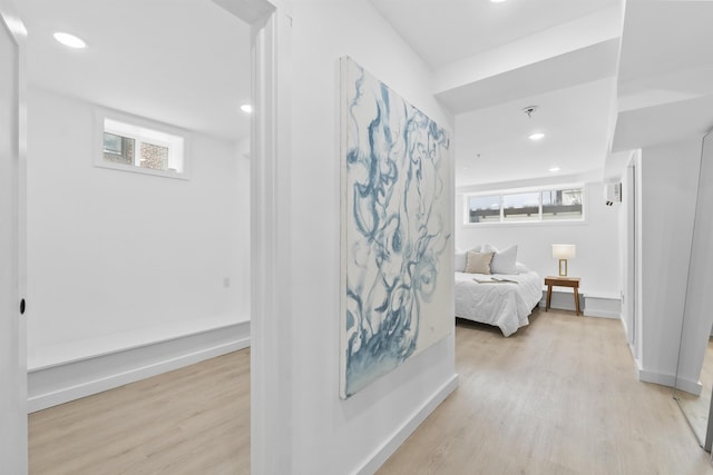 corridor with baseboards, light wood-style floors, and a healthy amount of sunlight