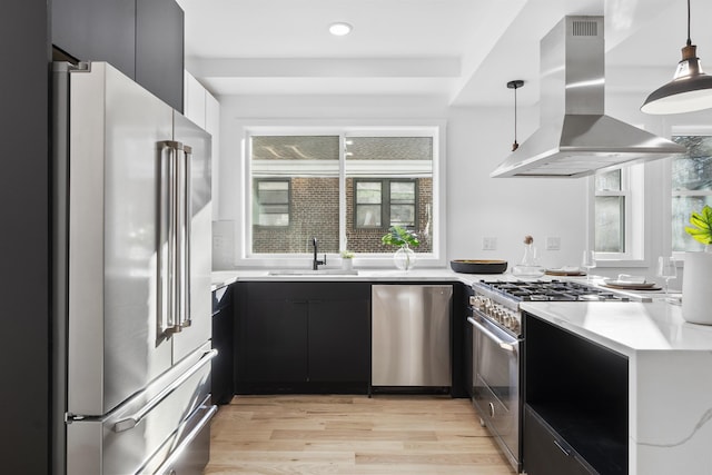 kitchen with a sink, light countertops, island exhaust hood, stainless steel appliances, and modern cabinets