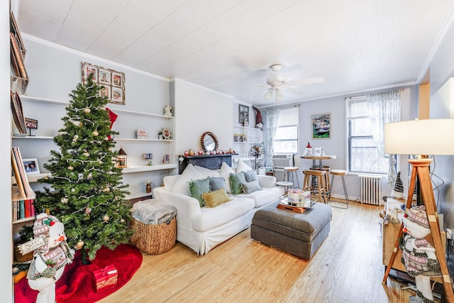 living room with radiator heating unit, ceiling fan, ornamental molding, and wood-type flooring