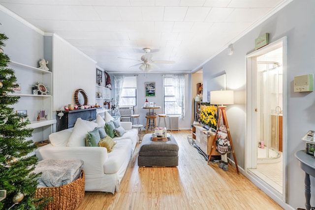 living room with ceiling fan, light wood-type flooring, crown molding, and radiator