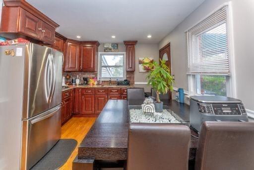 kitchen featuring decorative backsplash, stainless steel fridge, light wood-type flooring, and sink