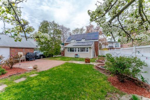 rear view of house with solar panels and a lawn