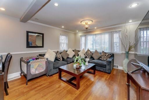 living room with a wealth of natural light, hardwood / wood-style floors, and ornamental molding