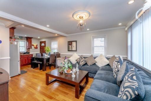 living room with crown molding and light wood-type flooring