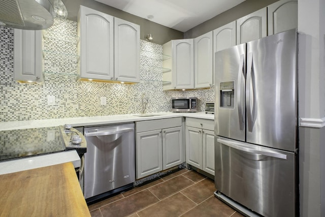 kitchen featuring backsplash, white cabinets, sink, dark tile patterned floors, and appliances with stainless steel finishes