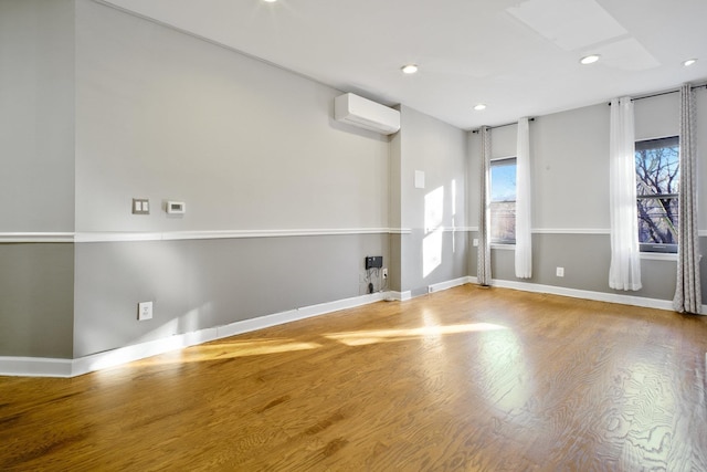 spare room featuring wood-type flooring and a wall unit AC