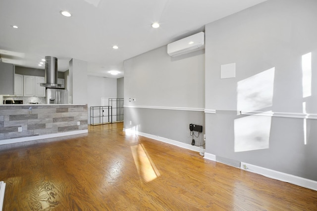 interior space with a wall mounted air conditioner and hardwood / wood-style floors