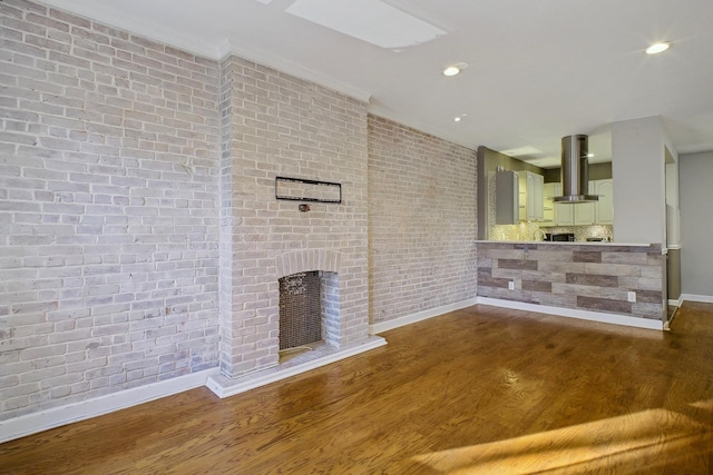 unfurnished living room with dark hardwood / wood-style floors, brick wall, and a brick fireplace