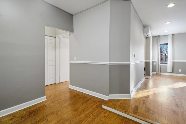 corridor with a wall unit AC and wood-type flooring