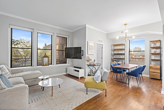 living room with a chandelier, wood finished floors, a wealth of natural light, and crown molding