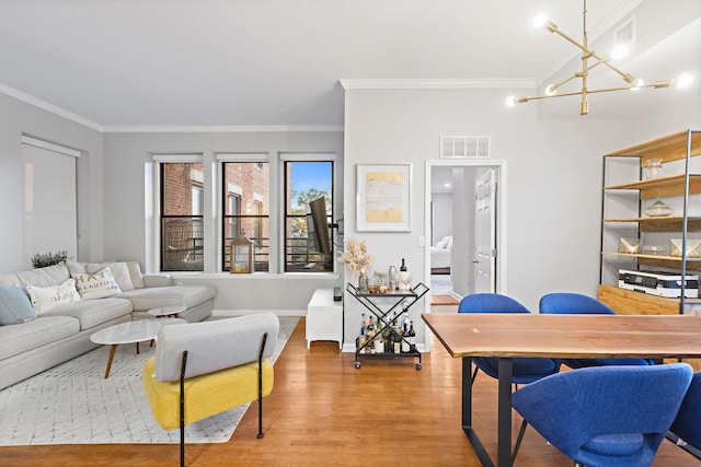 living room featuring crown molding, visible vents, a chandelier, and wood finished floors