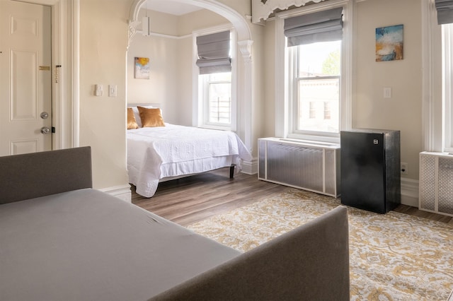 bedroom with baseboards, light wood-style floors, and radiator