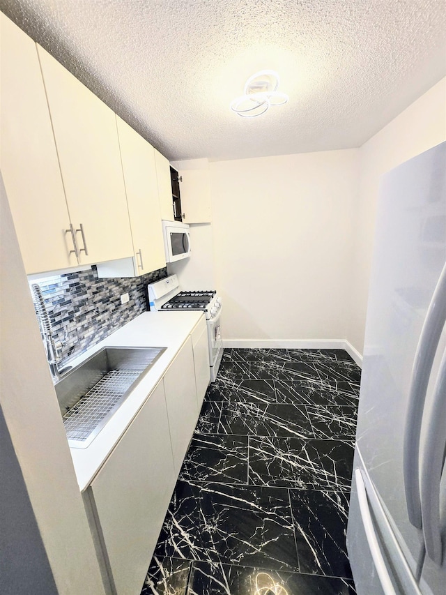 interior space with decorative backsplash, white appliances, and a textured ceiling