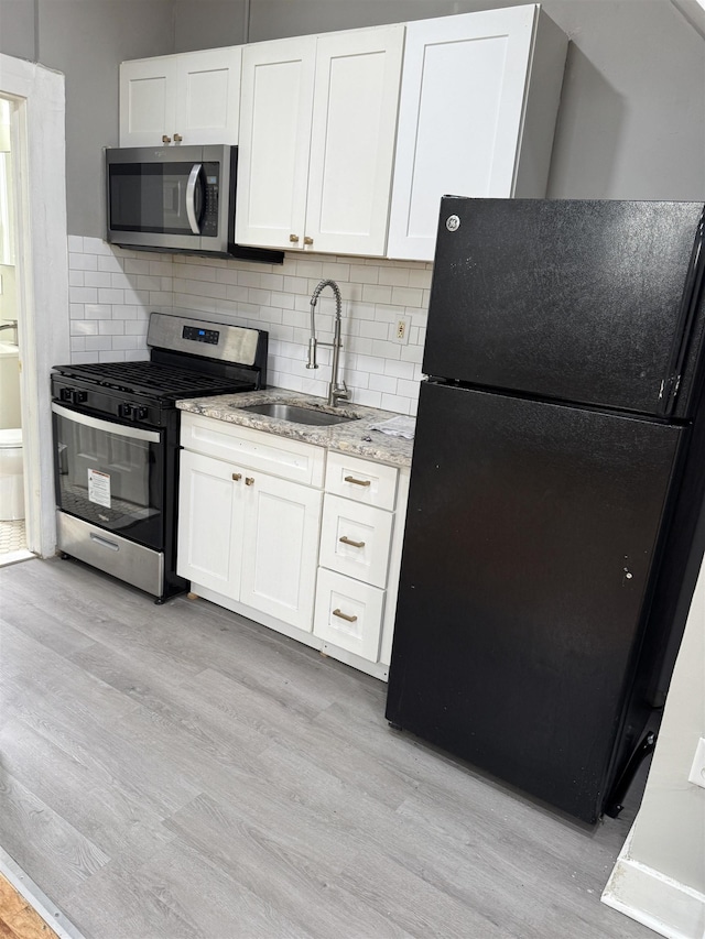 69 Jewett Ave, Jersey City, NJ 07304 - kitchen with stainless steel appliances, a sink, light wood-style floors, and white cabinets