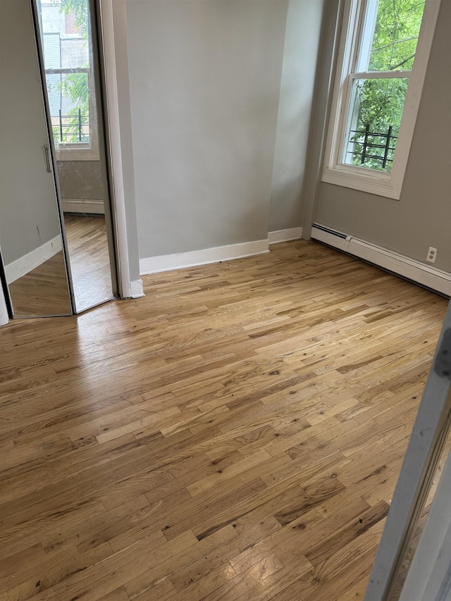 69 Jewett Ave, Jersey City, NJ 07304 - empty room with healthy amount of natural light, a baseboard heating unit, baseboards, and light wood-style floors