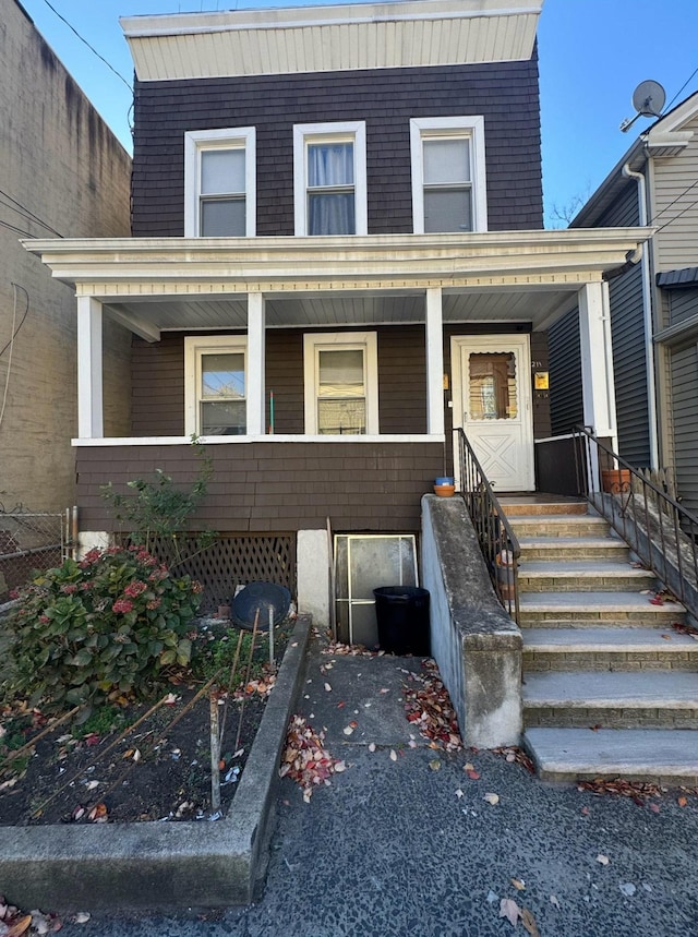 view of front of property featuring covered porch and mansard roof