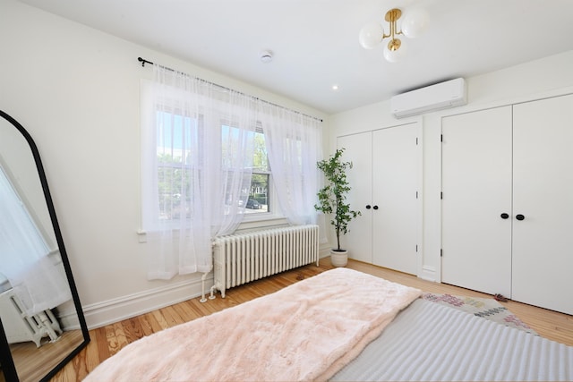 372 Webster Ave, Jersey City, NJ 07307 - bedroom with radiator, an AC wall unit, multiple closets, and light wood-style flooring