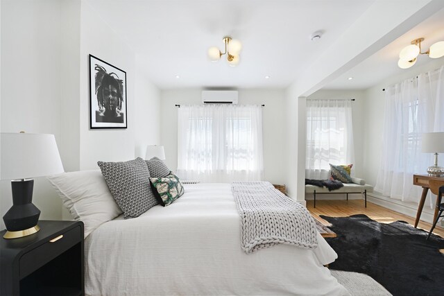 372 Webster Ave, Jersey City, NJ 07307 - bedroom with a wall unit AC, multiple windows, and wood finished floors