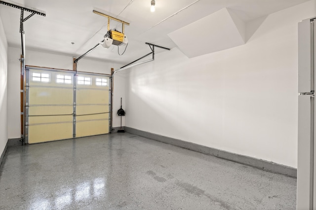 garage with a garage door opener, freestanding refrigerator, and baseboards