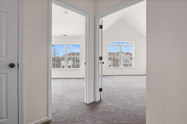 hall featuring baseboards, vaulted ceiling, and carpet