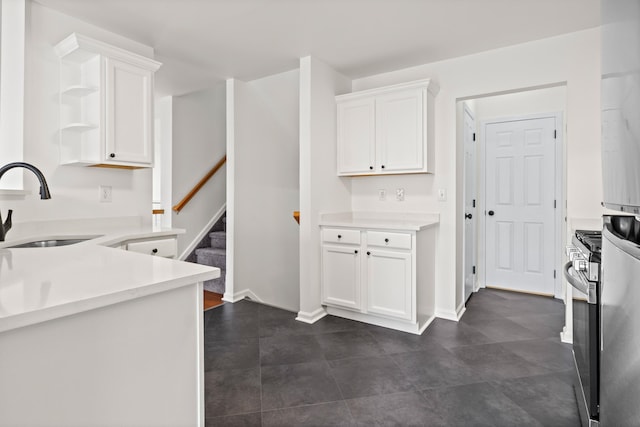 kitchen featuring white cabinets, stainless steel range with gas cooktop, a sink, open shelves, and light countertops
