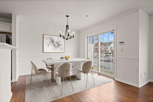 dining space with baseboards, crown molding, a chandelier, and wood finished floors