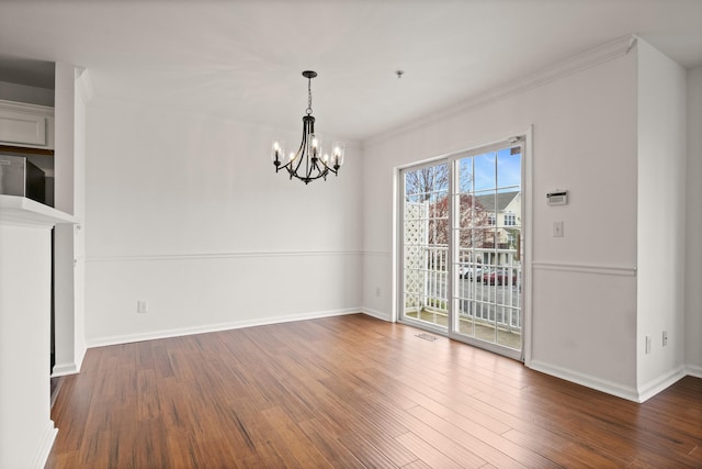 unfurnished dining area featuring wood finished floors, visible vents, crown molding, baseboards, and a chandelier