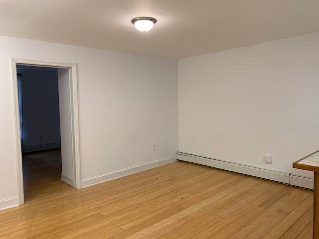 empty room featuring light wood-type flooring and a baseboard radiator