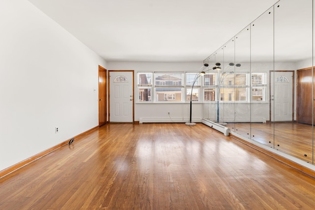 unfurnished living room featuring hardwood / wood-style flooring and a baseboard heating unit