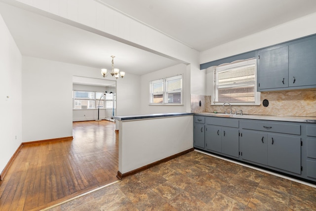 kitchen with sink, pendant lighting, a chandelier, gray cabinets, and decorative backsplash