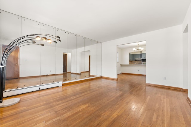 unfurnished living room featuring baseboard heating, a chandelier, and light wood-type flooring