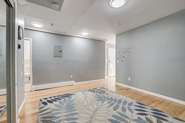 unfurnished room featuring electric panel, baseboard heating, and light hardwood / wood-style flooring