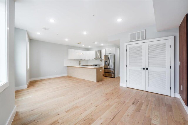 443 Bergen Ave Unit C3, Jersey City, NJ 07304 - kitchen with a peninsula, visible vents, wall chimney exhaust hood, stainless steel fridge, and light countertops