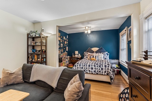 bedroom with light wood-type flooring, a baseboard radiator, and ceiling fan