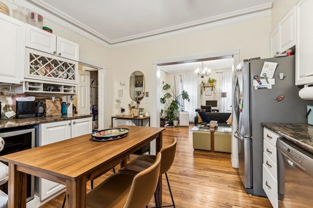 kitchen featuring crown molding, white cabinetry, appliances with stainless steel finishes, light wood-type flooring, and beverage cooler